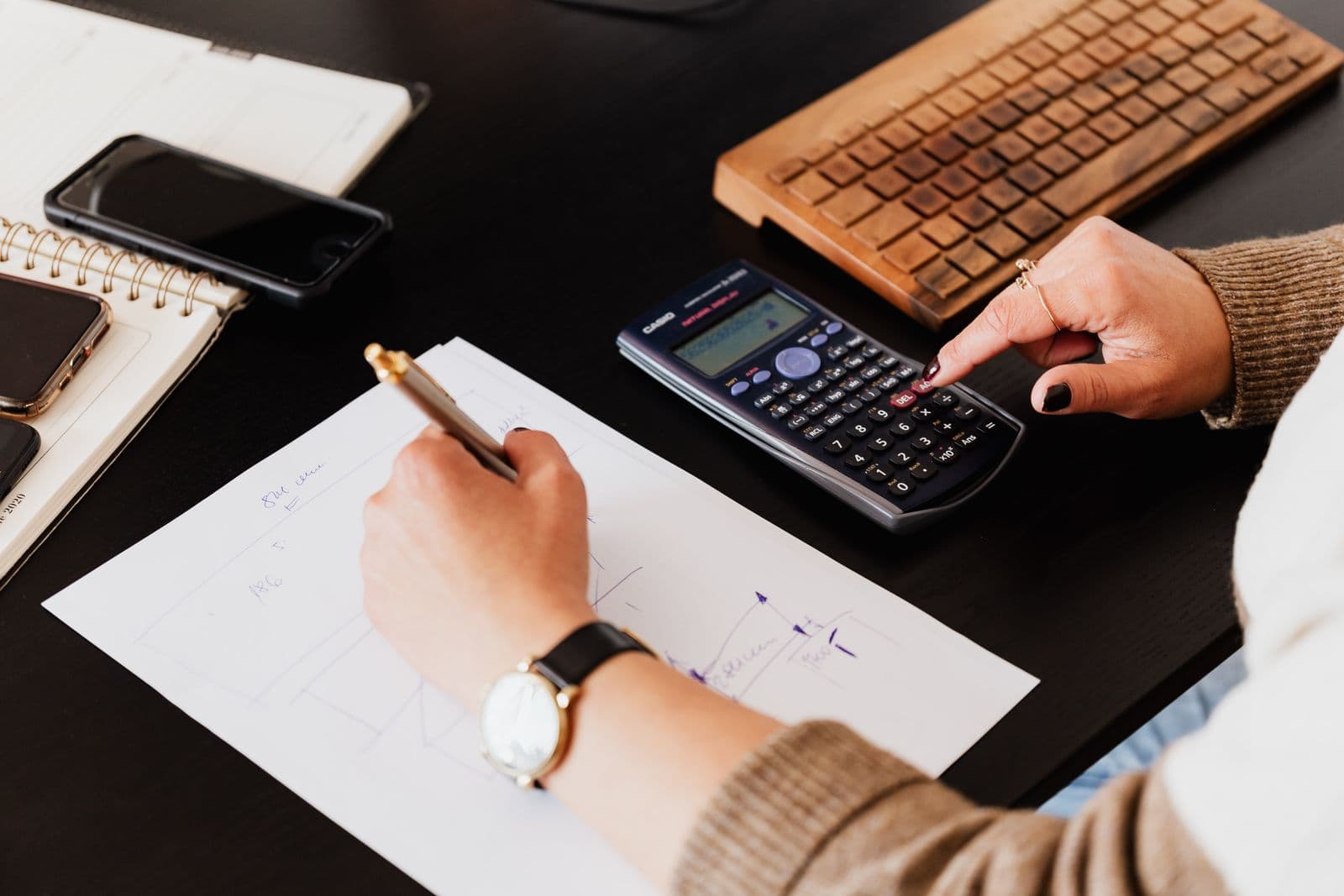 Person working through paperwork with a calculator and keyboard at a desk
