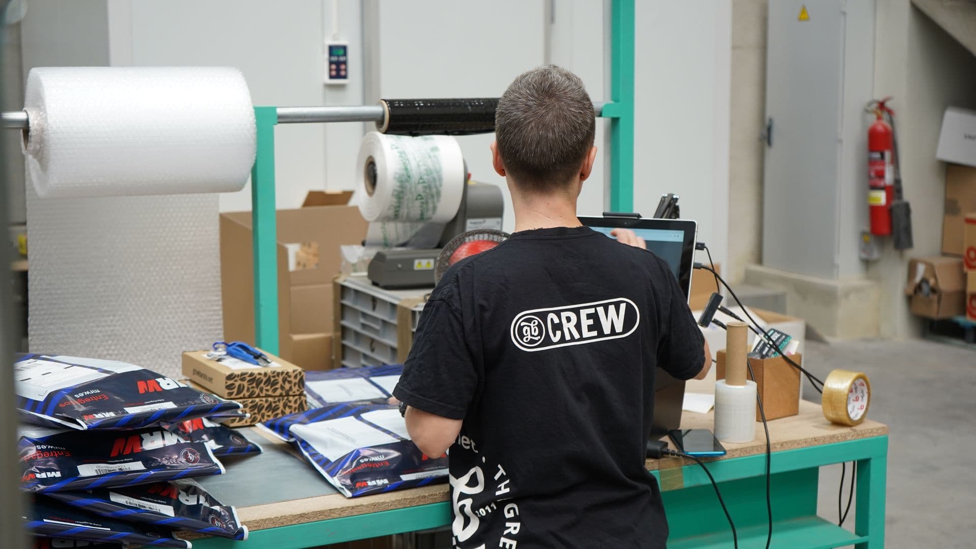 Business owner packing customer orders at a workbench in a small warehouse