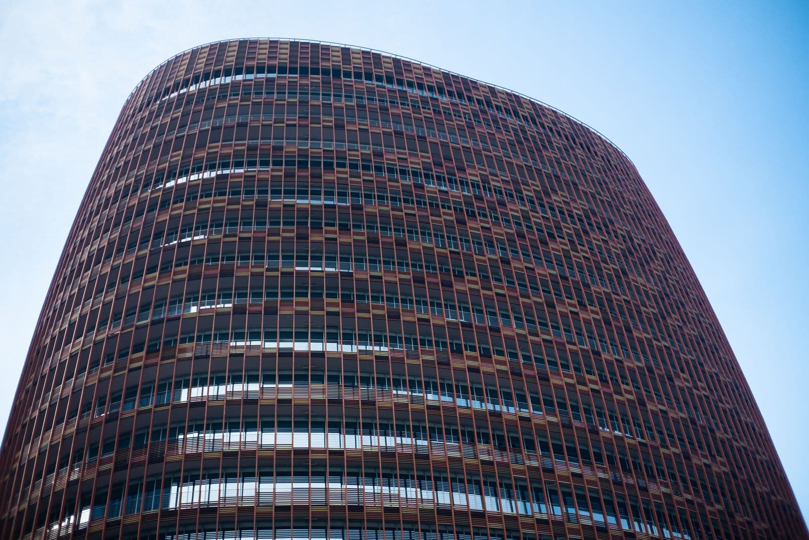 Curved brick and glass facade of a commercial office building against a clear sky